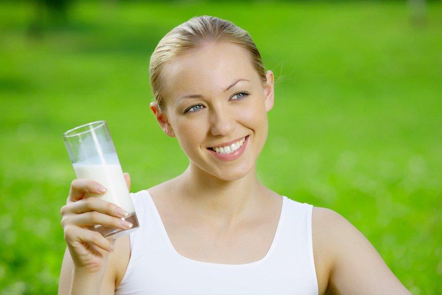 Girl with a bottle of kefir on a background of green grass