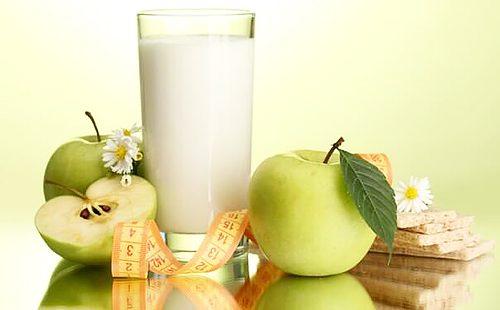 Un vaso de leche agria y manzanas verdes.