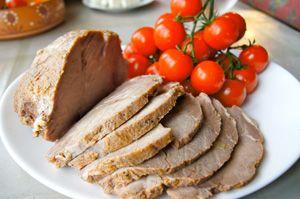 Boiled pork with cherry tomatoes on a white plate