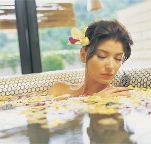 Girl lies in a bath with rose petals