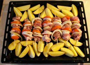 Skewers on skewers with potatoes on a baking sheet