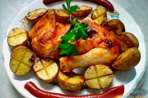 Pollo con papas al horno y salsa de tomate en un plato