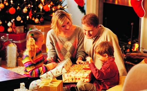 Des enfants déballent des cadeaux près de l'arbre de Noël avec leurs parents