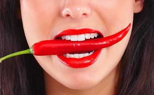 Djevojka koja pokušava jesti crvenu papriku