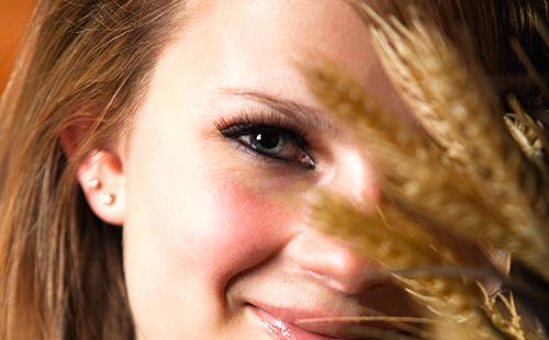 Chica escondida detrás de espiguillas de trigo