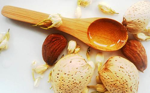 Flores, nueces y mantequilla dorada en una cuchara de madera
