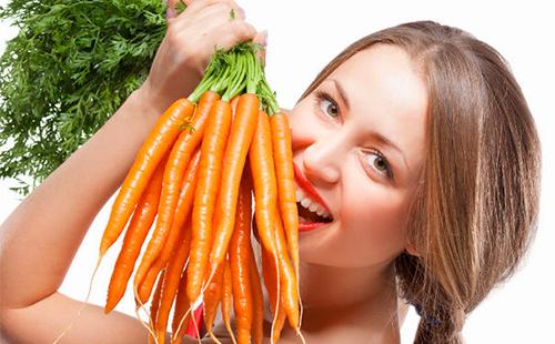 Cheerful girl holds a whole bunch of carrots