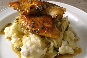 Juicy slice of chicken rises on a white hill of mashed potatoes