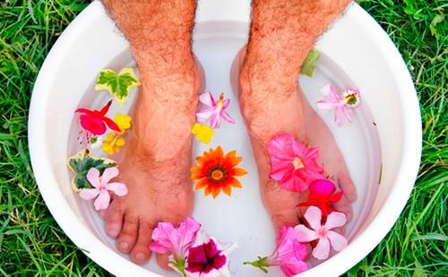 Piernas de hombre en un lavabo con agua y flores.