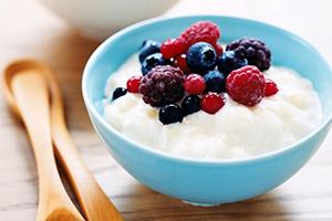 Milk porridge with wild berries in a blue bowl