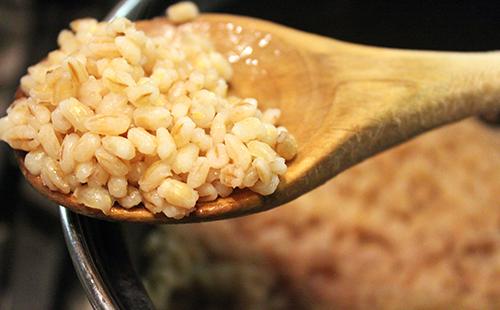 A large wooden spoon is full of finished pearl barley