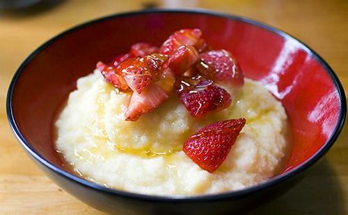 Porridge with chopped strawberries in a dark red plate