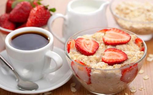 Desayuno glamoroso con avena, fresas, crema y café.