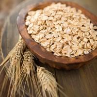 Spikelets of oats and rolled grain in a brown bowl