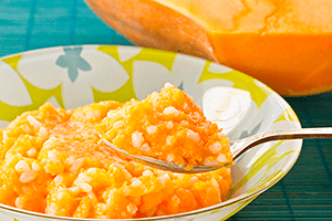 Svijetla narančasta kaša od lubenice s rižom u šarenom tanjuru
