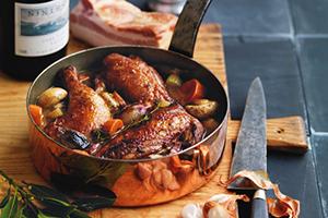 Plato francés gourmet con cebolla y hierbas, una botella de vino tinto al fondo