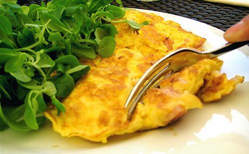 Omelet on a plate, fork and greens