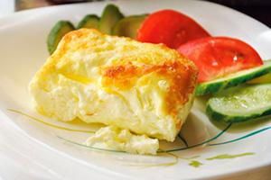 Lush omelet on a plate with slices of cucumbers and tomatoes