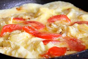 Omelette aux tomates, fromage et oignons