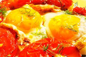 Huevos fritos con tomate y hierbas.