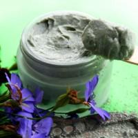 Black clay in a glass jar among violets