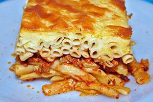 Slice of pasta casserole with minced meat on a blue plate