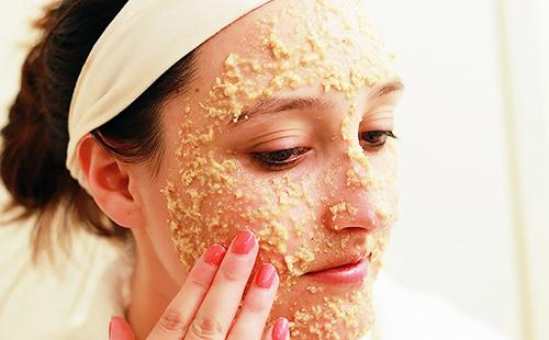 Woman with pink nails rubs oatmeal on her cheeks