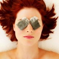 Red-haired woman with tea bags in front of her eyes