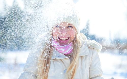 Djevojka u bijeloj kapi uživa u snijegu
