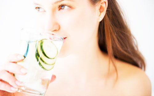 Girl drinks water with cucumbers