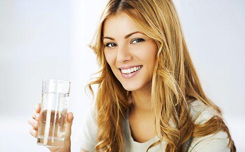 Niña sonriente sosteniendo un vaso de agua