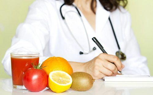 Fruits lie on a table in front of a doctor writing something