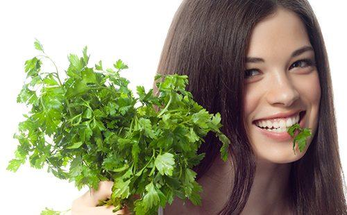Joyful girl holds out a bunch of parsley