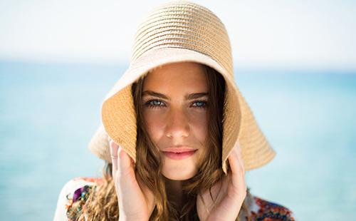 Chica junto al mar en un gran sombrero