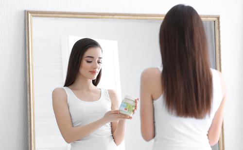 Girl holds a jar of coconut oil