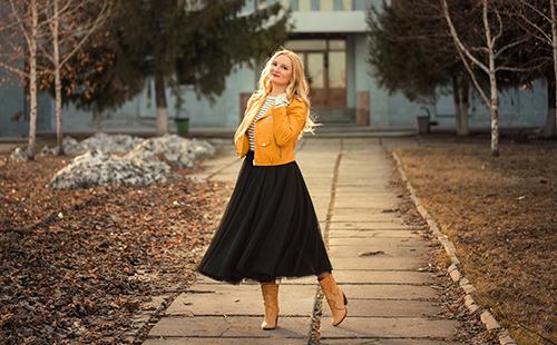 Anna in black and gold outfit poses on a cobblestone