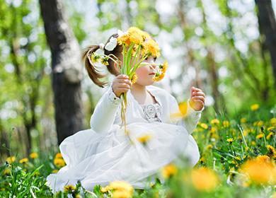 Girl in a white dress holds a bouquet of dandelions