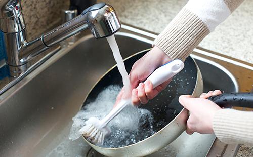 Woman washes a frying pan