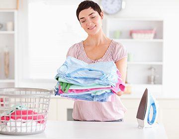 Mujer satisfecha con una pila de ropa limpia