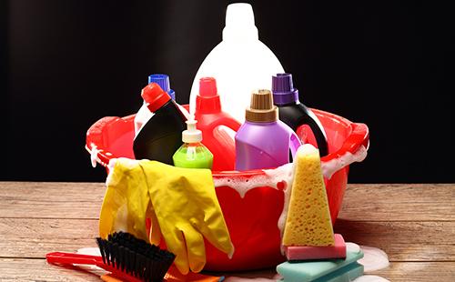A set of household cleaners in a red basin