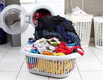 Cesto de la ropa delante de la lavadora