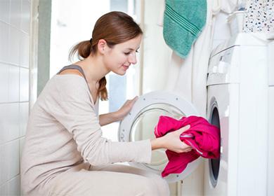Žena stavlja crveni džemper u perilicu rublja