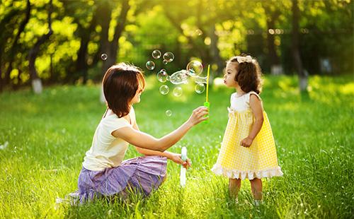 Mom and daughter play with soap bubbles