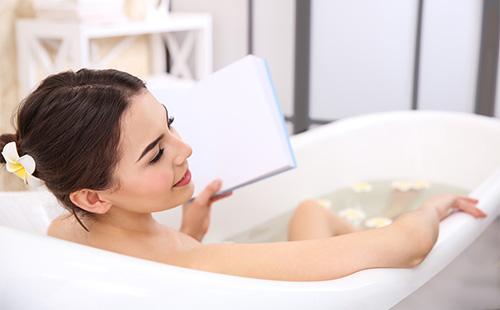 Girl reads while taking a bath