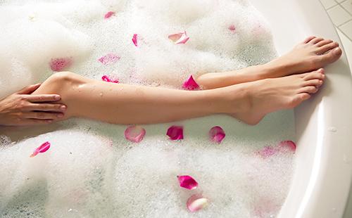Girl's legs in a foam bath with pink petals