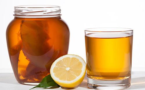 Kombucha en una jarra, limón y una taza con té