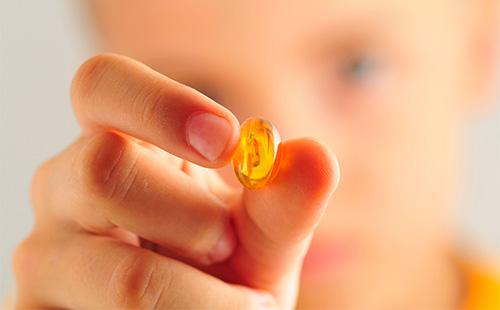 Capsule of fish oil in the hand of a child