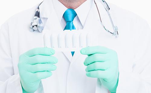 Las manos del médico en guantes sostienen velas médicas