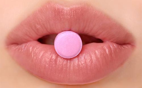 Pink tablet on the lips