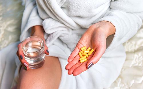Girl holds yellow capsules with medicine in hand